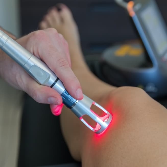 Physiotherapist applying laser therapy to a patient's shoulder.